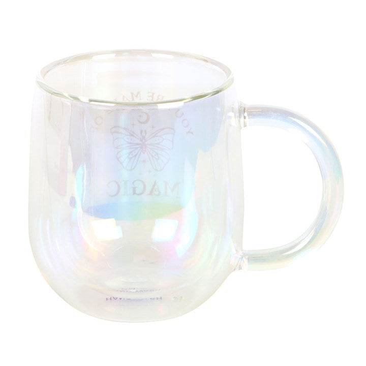 A clear double-walled glass mug with an iridescent interior, featuring a gold butterfly design and the phrase "You are made of magic" in gold lettering. The mug has a smooth handle and a modern, rounded shape.