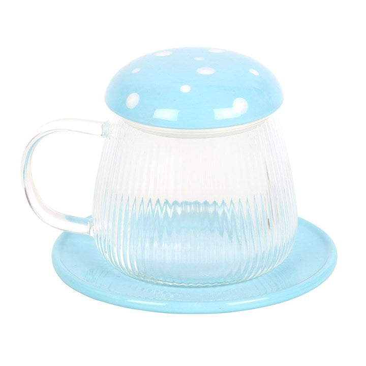 A whimsical glass mug with vertical ribbing, topped with a blue mushroom cap-style lid featuring white polka dots. The mug comes with a matching blue coaster and has a clear handle, creating a fun and cheerful aesthetic perfect for tea or coffee.
