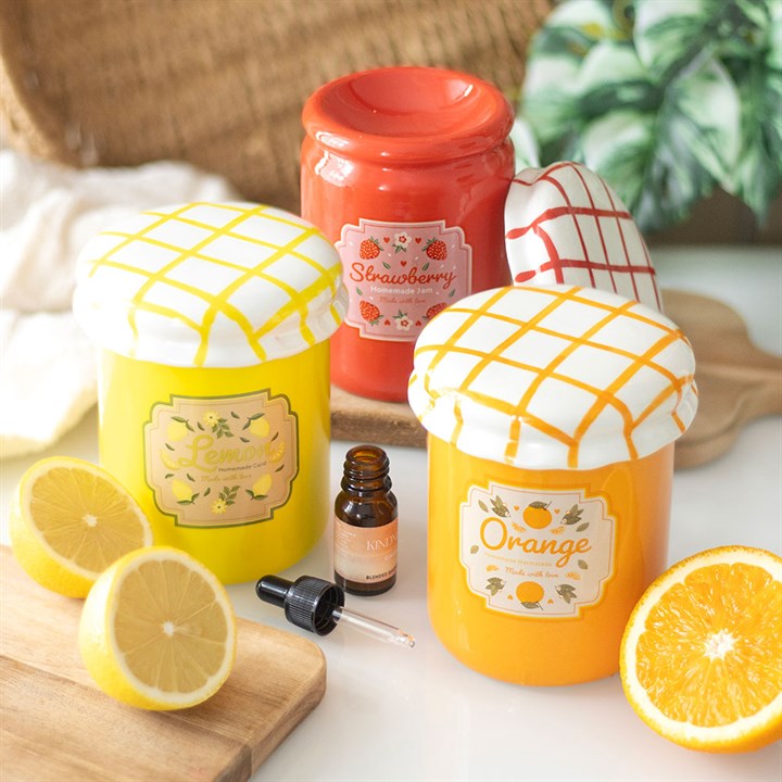 A strawberry jam-themed oil burner and wax warmer designed to look like a vintage jam jar, featuring a glossy red finish, a white ceramic lid with a red crisscross pattern, and a charming strawberry label.