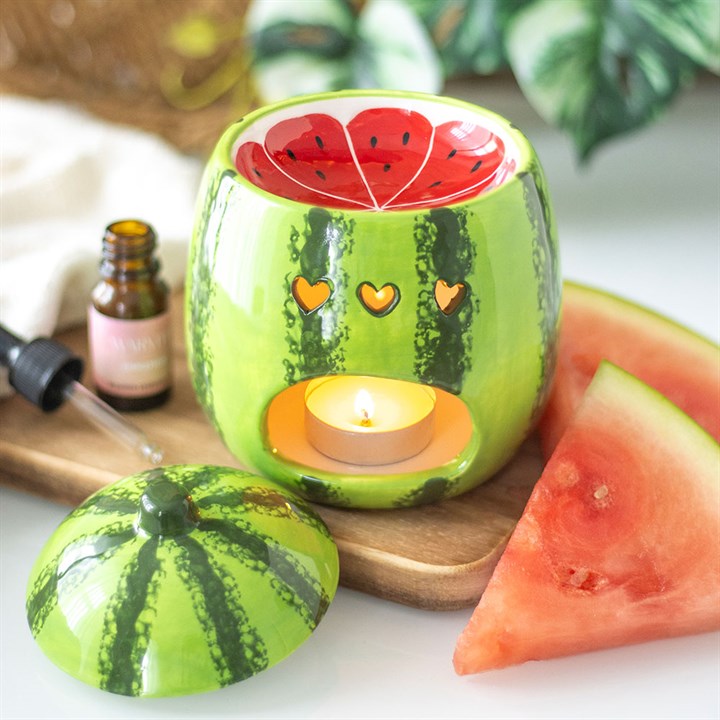 A beautifully designed watermelon-shaped scented candle housed in a glossy ceramic jar with a removable lid resembling a watermelon rind.