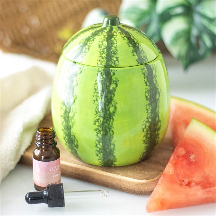 A beautifully designed watermelon-shaped scented candle housed in a glossy ceramic jar with a removable lid resembling a watermelon rind.