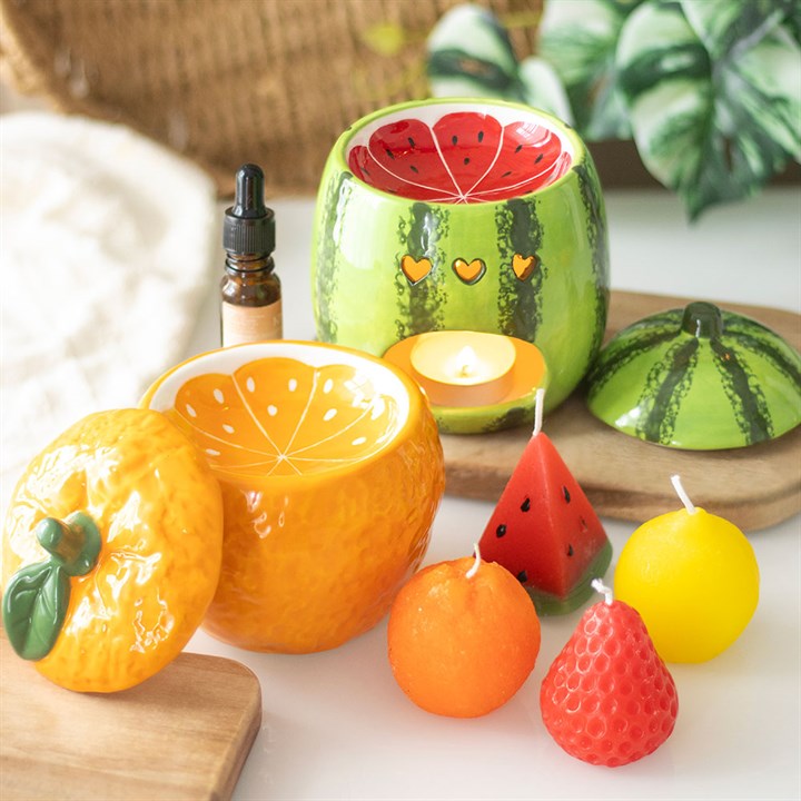 A beautifully designed watermelon-shaped scented candle housed in a glossy ceramic jar with a removable lid resembling a watermelon rind.