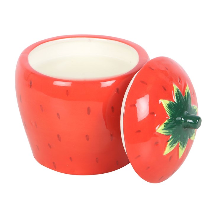 A beautifully designed strawberry-shaped scented candle housed in a glossy ceramic jar with a removable lid featuring a green leafy top.