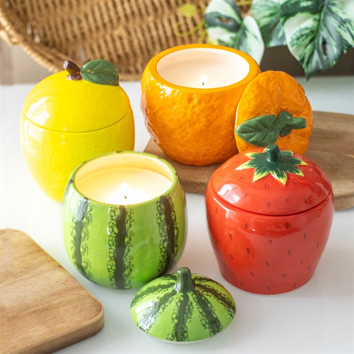 A beautifully designed strawberry-shaped scented candle housed in a glossy ceramic jar with a removable lid featuring a green leafy top.