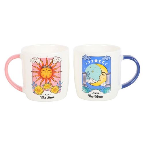A set of two ceramic mugs inspired by tarot cards. One mug features the Sun card with a bright sun face, pink handle, and floral accents. The other displays the Moon card with a crescent moon and serene night sky, paired with a blue handle. Both have a white base and colourful celestial artwork.