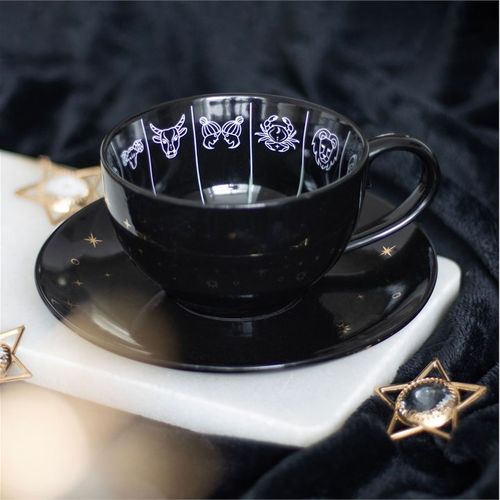 Black celestial teacup and saucer set featuring an astrology wheel with zodiac signs in white and gold detailing, designed for tea leaf reading and divination. 500ml capacity