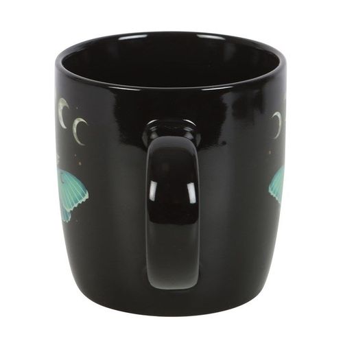 A glossy black ceramic mug featuring a detailed illustration of a teal luna moth, surrounded by moon phases, stars, and floral accents. The design evokes a mystical, nature-inspired aesthetic.