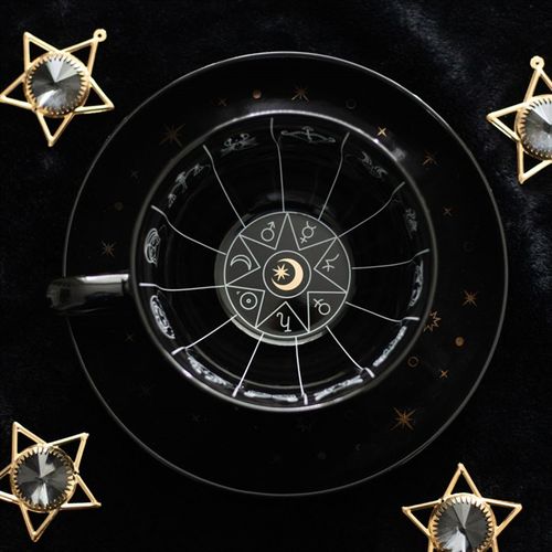 Black celestial teacup and saucer set featuring an astrology wheel with zodiac signs in white and gold detailing, designed for tea leaf reading and divination. 500ml capacity
