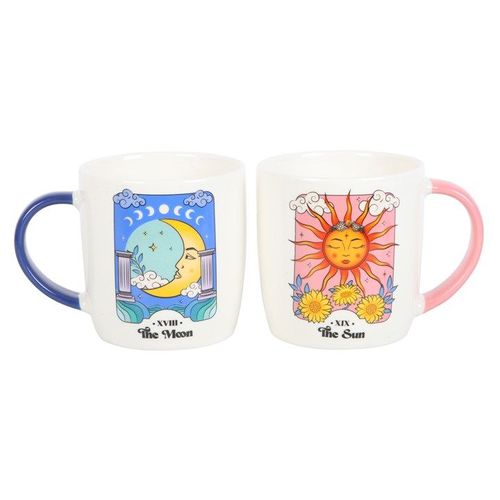 A set of two ceramic mugs inspired by tarot cards. One mug features the Sun card with a bright sun face, pink handle, and floral accents. The other displays the Moon card with a crescent moon and serene night sky, paired with a blue handle. Both have a white base and colourful celestial artwork.
