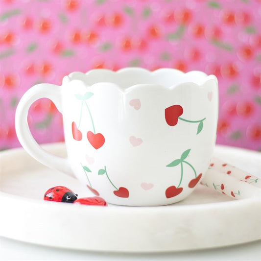 White ceramic scalloped mug featuring a charming cherry print design, perfect for enjoying coffee, tea, or hot cocoa with a touch of whimsy
