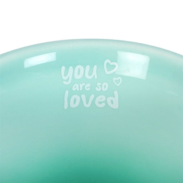 Mint green ceramic mug featuring a happy face design on the front and an uplifting 'You are so loved' message inside the rim, perfect for brightening your day or as a thoughtful gift