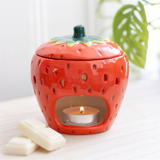 A ceramic strawberry-shaped oil burner with a removable lid, featuring a glossy red finish with tiny seed details and a green leafy top. The playful and vibrant design makes it a charming addition to any home décor.