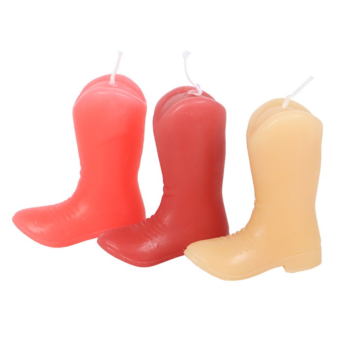 A set of three unscented decorative candles shaped like cowboy boots in shades of pink and peach. Each boot features Western-themed designs and phrases like "Howdy Cowboy" and "Stay Wild." Displayed on a wooden surface with soft background decor, adding a playful country charm.