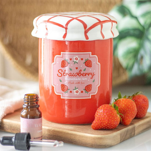 A strawberry jam-themed oil burner and wax warmer designed to look like a vintage jam jar, featuring a glossy red finish, a white ceramic lid with a red crisscross pattern, and a charming strawberry label.