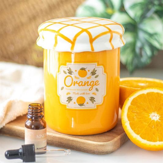 A vintage-style orange marmalade oil burner and wax warmer designed to resemble a jam jar, featuring a bright orange finish, a charming fruit label, and a white ceramic lid with a yellow crisscross pattern.