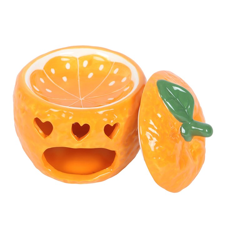 A ceramic orange-shaped oil burner with a glossy finish, featuring cut-out heart shapes that allow the light from a tealight candle to shine through.