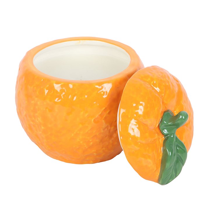 A beautifully designed orange-shaped scented candle housed in a glossy ceramic jar with a removable lid, featuring a green leaf accent. 