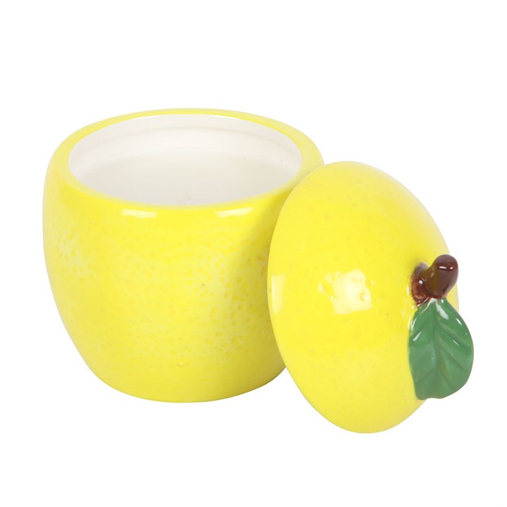 A lemon-shaped scented candle in a glossy ceramic jar with a removable lid, featuring a green leaf accent. 