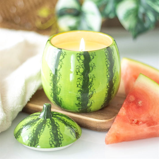 A watermelon-shaped scented candle in a glossy ceramic jar with a removable lid, featuring a realistic green rind design.