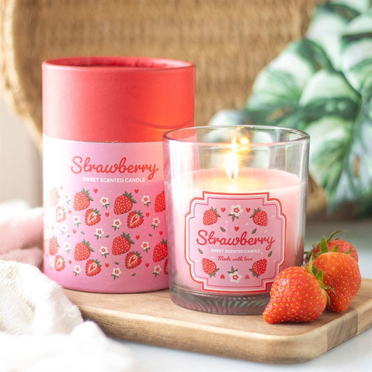A strawberry-scented candle in a transparent glass jar with a pink floral and strawberry print label