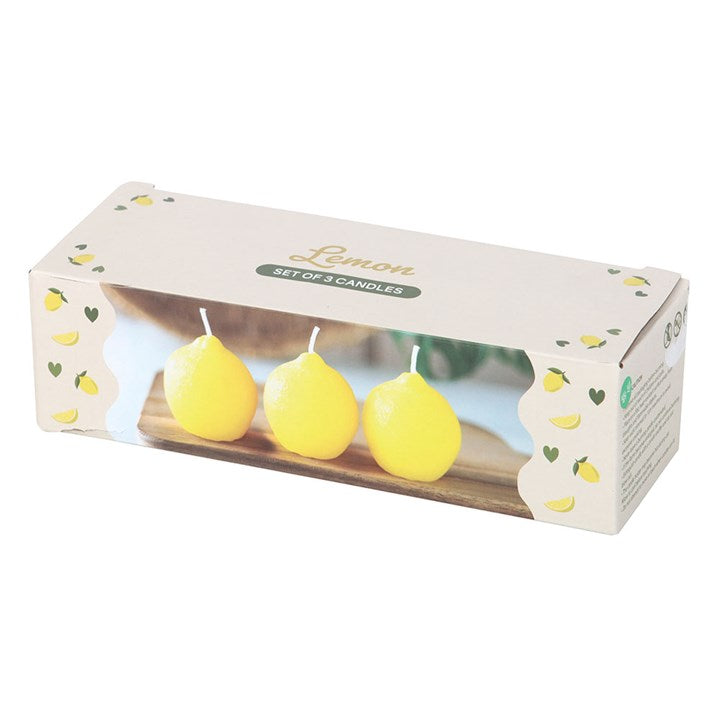 A set of three unscented, lemon-shaped candles with a smooth, glossy texture, placed on a wooden board. The candles have a bright yellow hue and white wicks, resembling real lemons