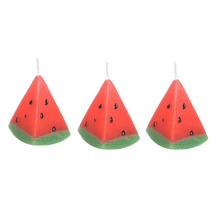 A set of three unscented, watermelon-shaped candles with a triangular design, featuring a red wax body with black seed-like details and a green base