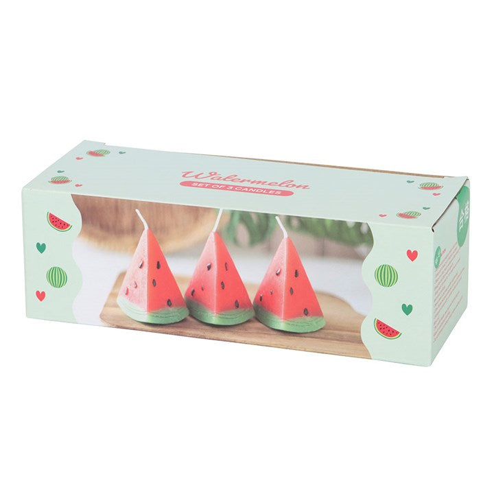 A set of three unscented, watermelon-shaped candles with a triangular design, featuring a red wax body with black seed-like details and a green base