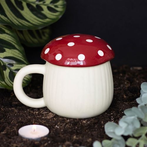 A novelty ceramic mug shaped like a mushroom, with a cream-colored base and a glossy red lid topped with white polka dots. The design mimics a toadstool, giving it a playful, whimsical look.