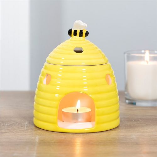 Yellow ceramic beehive-shaped oil burner with hexagonal cutouts and a cute bee accent on top, perfect for diffusing essential oils or wax melts to create a cozy atmosphere